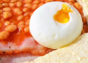 Cooked English full breakfast with an open poached egg