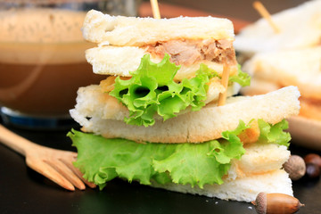 tuna sandwiches and hot coffee on black background