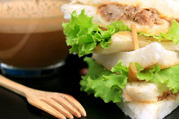 tuna sandwiches and hot coffee on black background