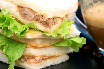 tuna sandwiches and hot coffee on black background