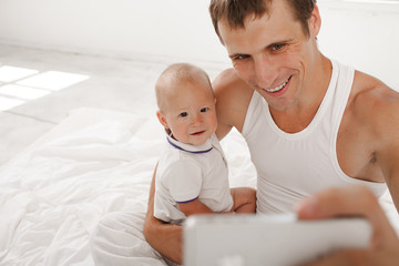 young father with his nine months old son on the bed at home