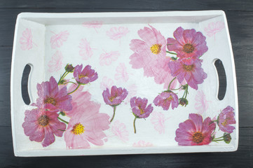 Decoupage decorated tray with flower pattern against  black wood