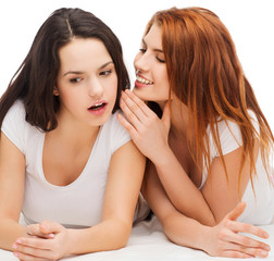 Obraz na płótnie Canvas two smiling girls whispering gossip