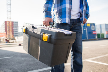 close up of builder carrying toolbox outdoors