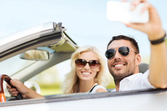 happy couple in car taking selfie with smartphone