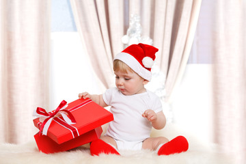 Baby santa holds a big red gift box