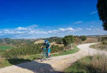 Fototapeta premium Mountain biker riding through Tuscan landscape