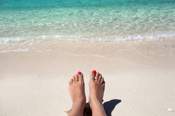Woman legs lying on sandy beach