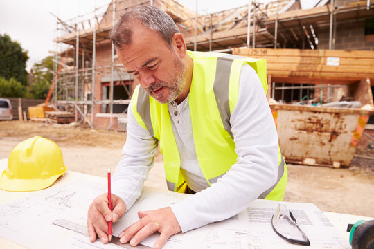 Construction Worker Looking At Plans On Building Site