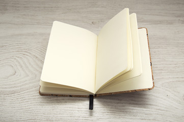 open notebook, blank, on wooden desk.