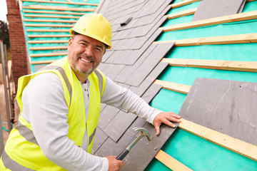 Construction Worker On Building Site Laying Slate Tiles - obrazy, fototapety, plakaty