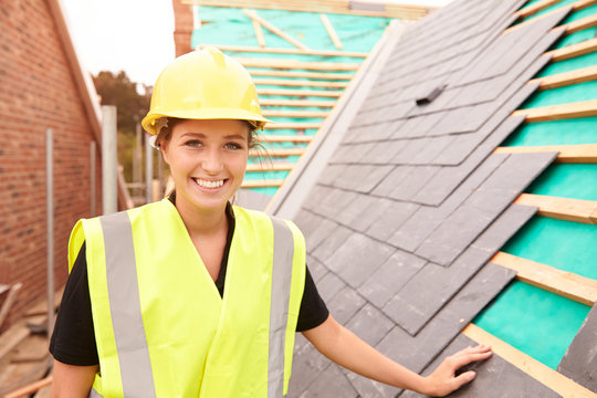 Female Construction Worker On Site Laying Slate Tiles