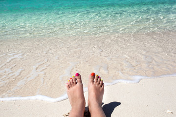 Woman legs lying on sandy beach