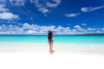 Fototapeta na wymiar Enjoying freedom. Beautiful woman on beach in summer hat