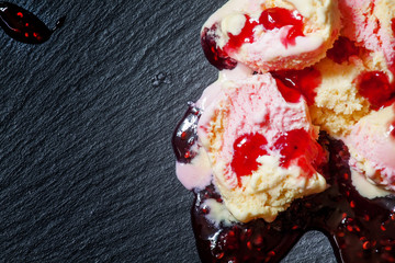 Ice cream of banana and raspberry melting on a dark background,