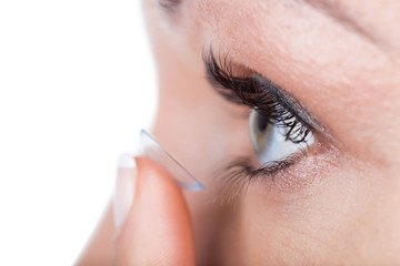 Woman eye with contact lens applying