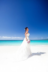 Fototapeta na wymiar Beautiful bride on white sandy beach, smiling and feeling happin
