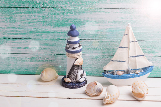 Decorative lighthouse,  sailing boat and marine items on wooden