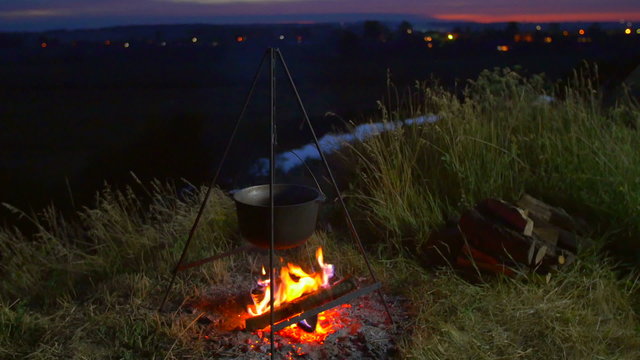 The cauldron with food on the fire by picturesque landscape backround
