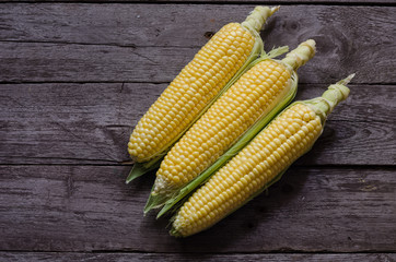 corn cob and green leaves on wooden background