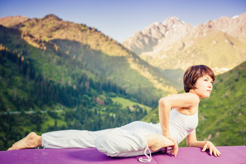 Inspired asian woman doing exercise of yoga at mountain range