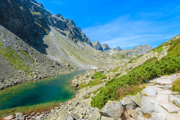 Fototapeta na wymiar Hiking trail along beautiful lake in summer landscape of Starolesna valley, High Tatra Mountains, Slovakia