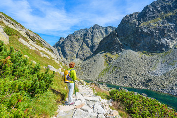 Young woman backpacker on hiking trail in summer landscape of High Tatra Mountains, Slovakia