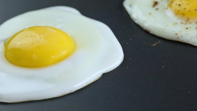 Cooking fried eggs on electric barbecue, salting and papering
