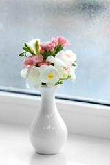 Beautiful spring flowers in vase on windowsill background