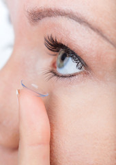 Woman eye with contact lens applying