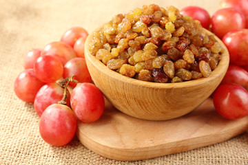Raisins in bowl with grapes on table close up