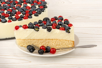 Cheesecake with  red currants and  blueberries  on the wooden background.