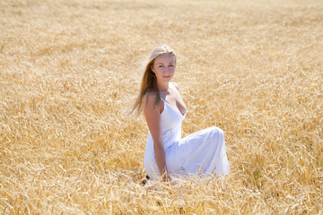 Young beautiful woman in a long white dress is sitting in a whea