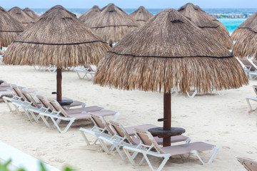 Sun umbrella and beds on caribbean beach in cloudy weather