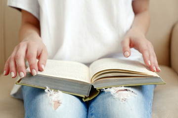 Woman reading book on sofa close up