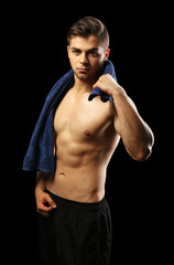 Fototapeta premium Muscle young man holding towel on dark background