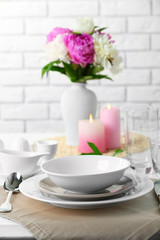 Fototapeta na wymiar Beautiful table setting with flowers in vase on brick wall background