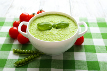Tasty peas soup and cherry tomatoes on table close up