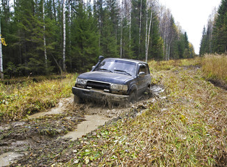 Fototapeta na wymiar Russian Plain Road in the heart of Siberia. Flailing at breakneck speed wheel off-road vehicle stuck in a swamp