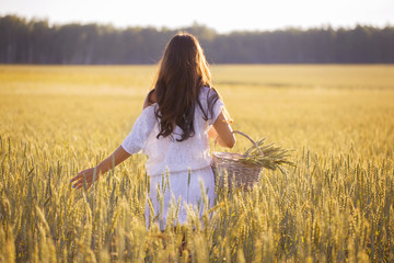 Girl in wheat field with wicker basket