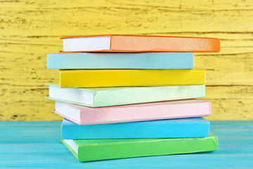 Colorful books on yellow wooden background