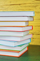 Stack of books on yellow wooden background