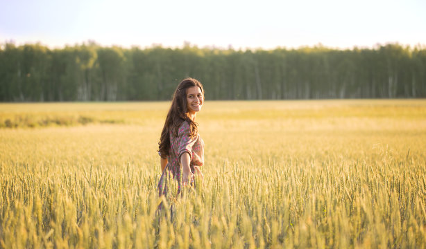 Smiling beautiful girl among the Golden wheat ears
