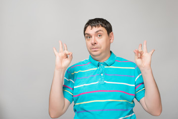 Gesturing OK sign. Cheerful young man   gesturing OK sign while standing against grey background