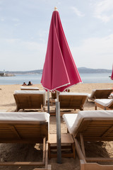 Pink umbrella and loungers on the beach