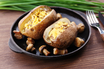 Baked potatoes with cheese and mushrooms on table close up