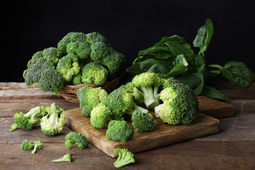 Fresh broccoli with spinach on wooden table close up
