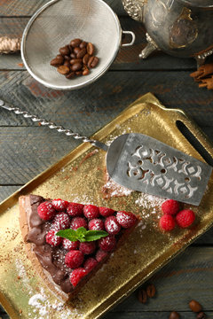 Piece of cake with Chocolate Glaze and raspberries on tray on wooden background