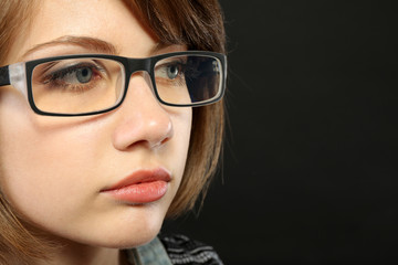 Attractive young woman with glasses on gray background
