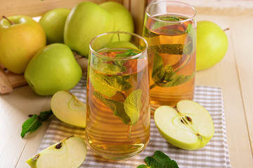 Glasses of apple juice with fruits and fresh mint on table close up